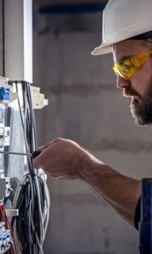 male-electrician-works-in-switchboard-with-an-electrical-connecting-cable(1) male-electrician-works-in-switchboard-with-an-electrical-connecting-cable(1)